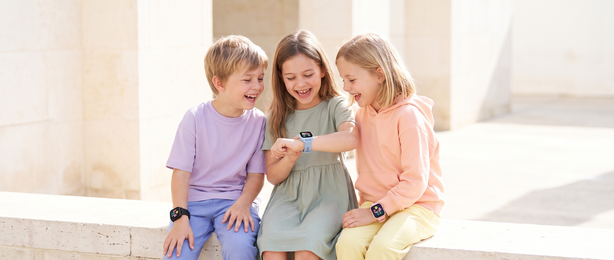 Trois enfants qui rient en regardant leurs montres ARKO Kids